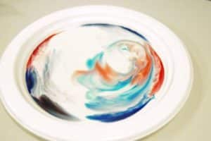 Milk rainbow science experiment - colours swirling on a plate