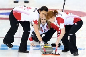 Three women in black pants red and white shirts representing Canada curling
