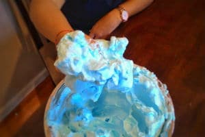 Person holding a handful of blue foam above a metal bowl full of blue foam