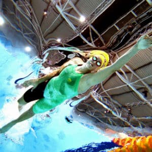 Commonwealth games swimmer in green and black mid stroke in the water looking up from bottom of pool