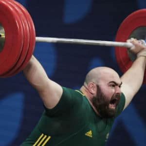 Australian weightlifter in green shirt lifts red weights at commonwealth games