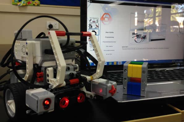 ev3 robot in front of a computer with a yellow and blue Lego brick on the keyboard
