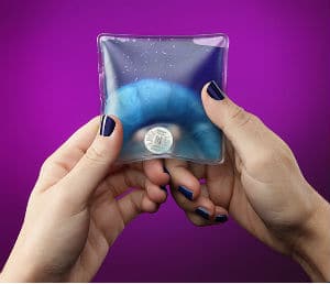 hands holding blue pocket warmer purple background