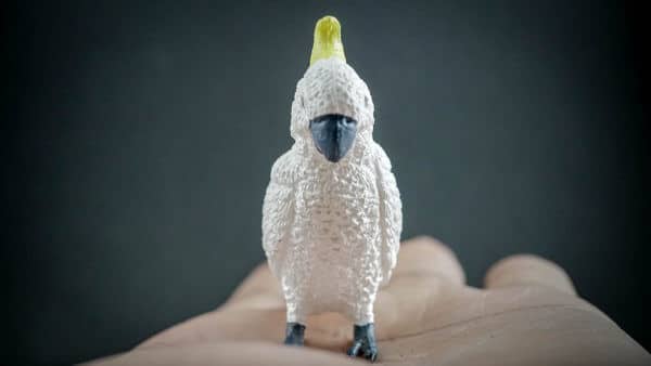 Sulfur-crested Cockatoo replica standing on a hand. Front view