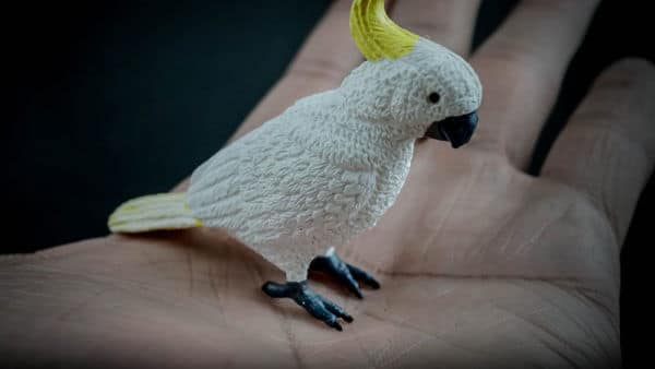 Sulfur-crested Cockatoo replica standing on a hand. Side view