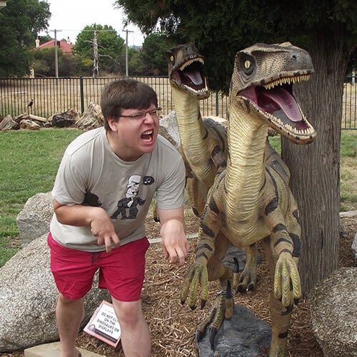 Ben standing next to two replica dinosaurs